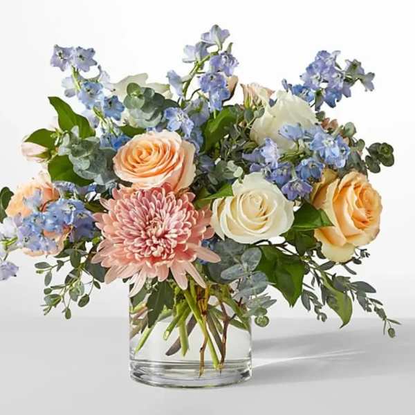 Mixed bouquet of roses, a pink chrysanthemum, and blue flowers in a glass vase
