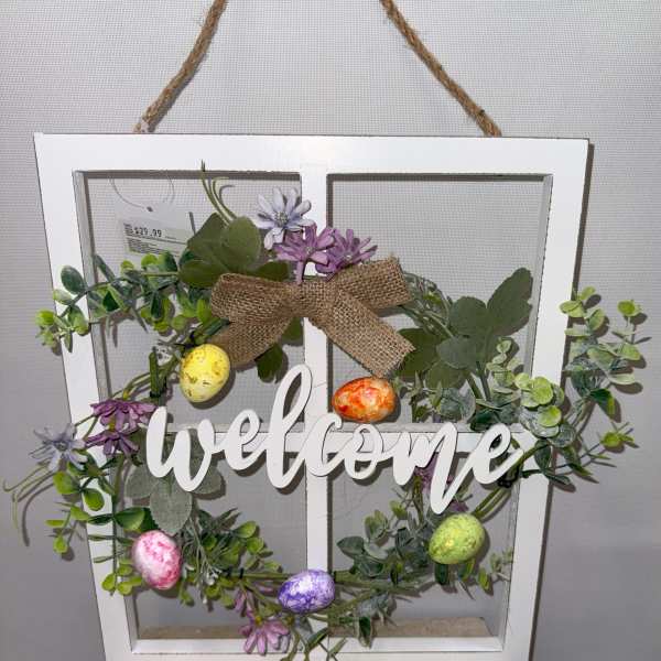 Decorative wreath in a white window frame with flowers, eggs, and a welcome sign