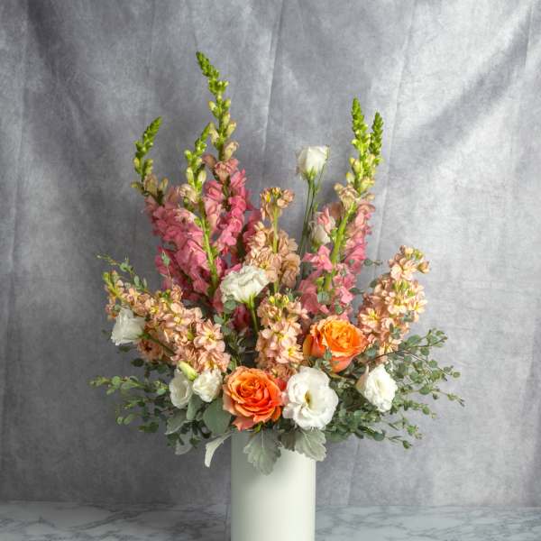 Mixed bouquet in a white vase with orange and white blooms