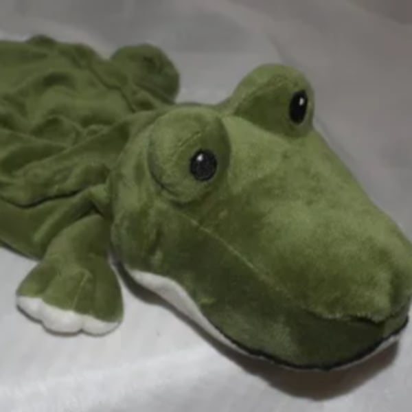 Plush green frog toy with large eyes lying on a light surface