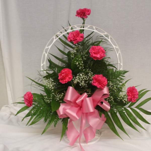 Pink carnations in a white basket with a pink ribbon