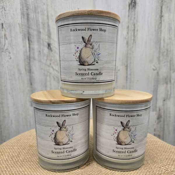 Three scented candles with rabbit labels stacked on burlap