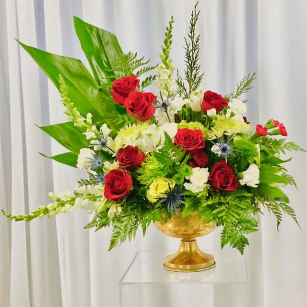 Red and white roses arranged in a gold pedestal vase