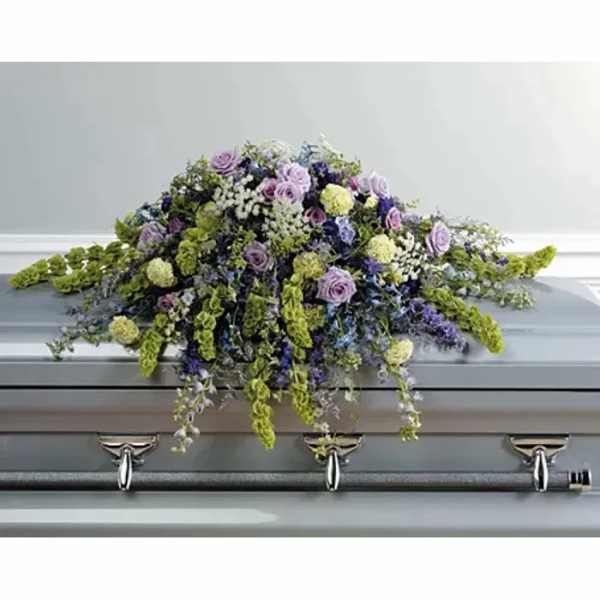 Lavender and green floral casket spray on a gray casket