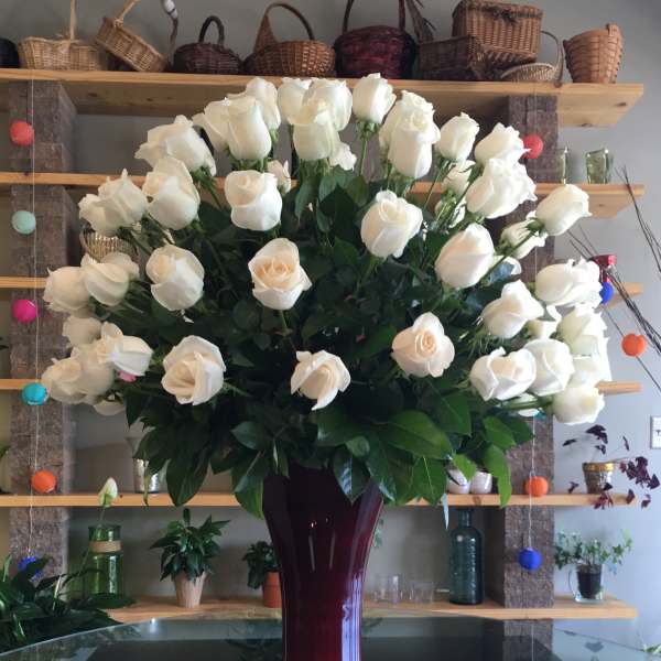 Large bouquet of white roses in a tall burgundy vase