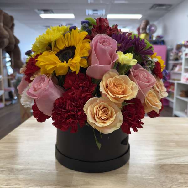 Mixed bouquet of sunflowers, roses, and carnations in a black box