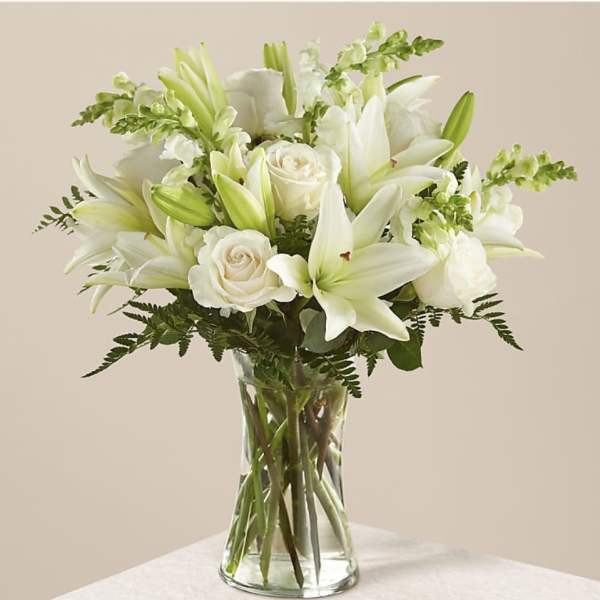 White lilies and roses arranged in a clear glass vase