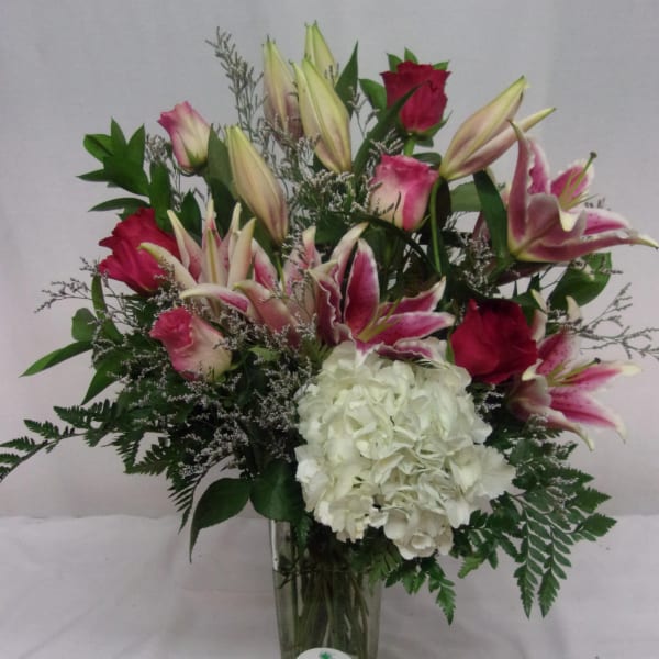 Pink lilies and roses with white hydrangea in a glass vase