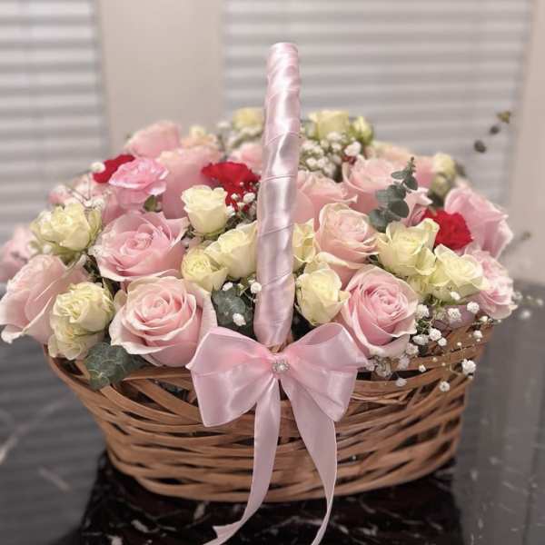 Basket of pink and cream roses with a pink ribbon handle