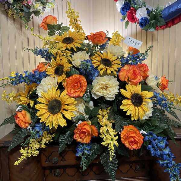 Large floral arrangement with sunflowers, orange roses, and blue flowers