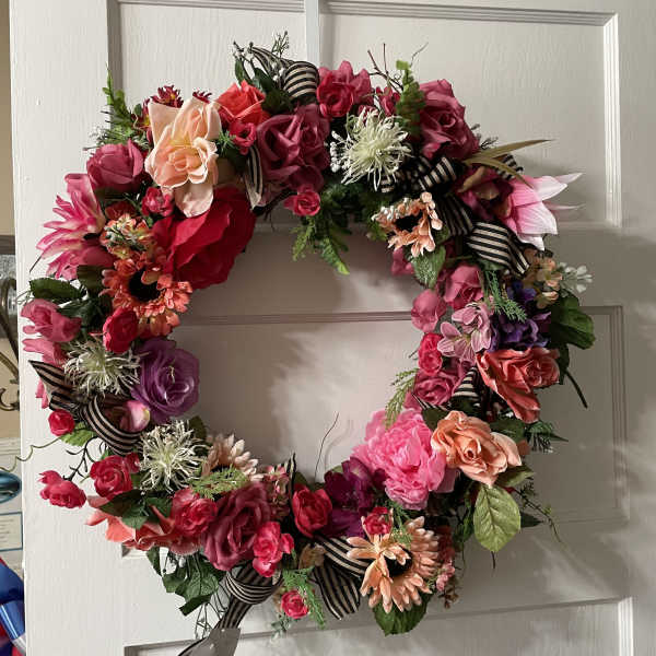 Floral wreath with pink, red, and peach blooms on a door