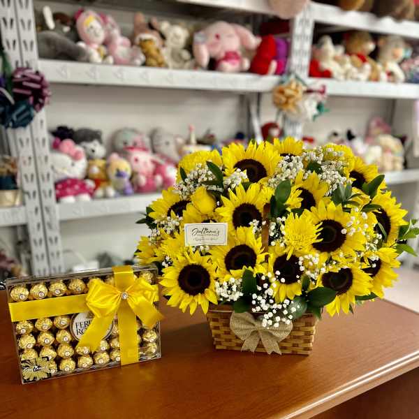 Sunflower arrangement in a wicker basket beside a box of chocolates
