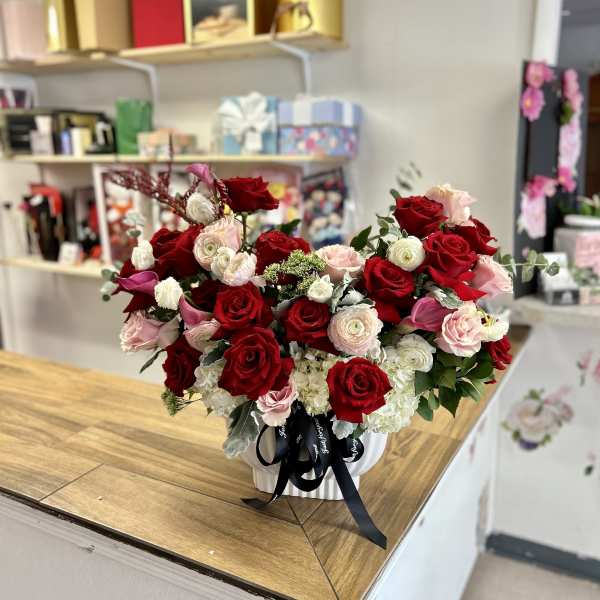 A large bouquet of red, pink, and white roses in a white vase