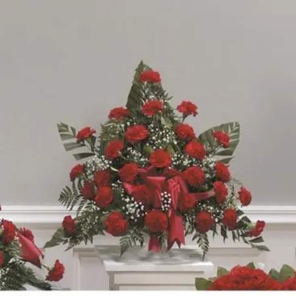 Red carnation arrangement with ribbon and greenery