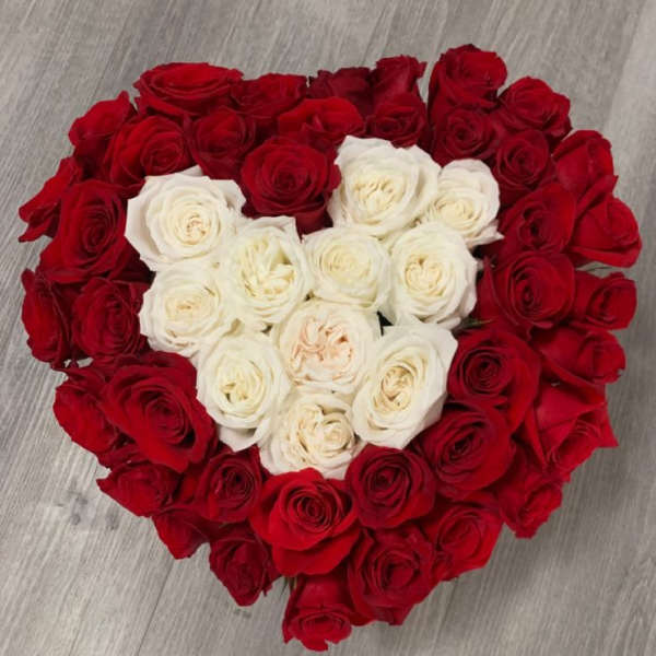 Heart-shaped bouquet of red and white roses on a wood floor