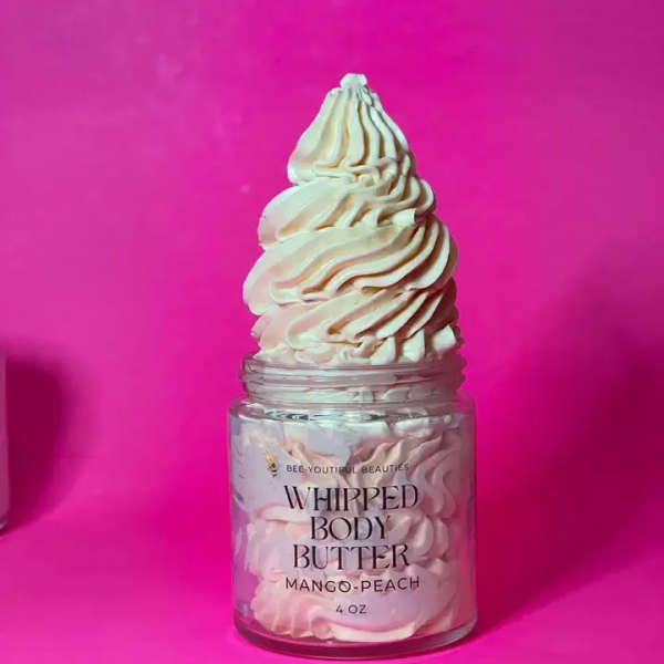 Jar of whipped body butter with a swirled cream top on a pink background