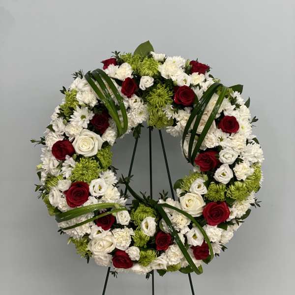 Circular wreath of red, white, and green flowers on a stand