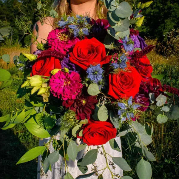 Bouquet of red roses, pink blooms, and blue flowers with eucalyptus