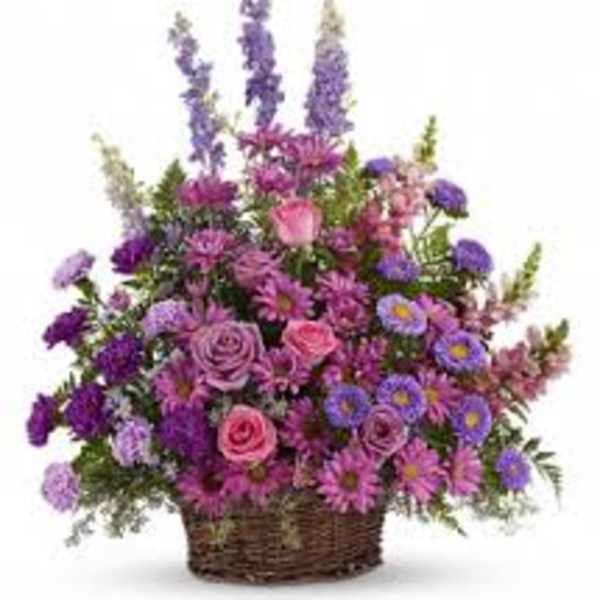 Purple and pink mixed flower arrangement in a wicker basket