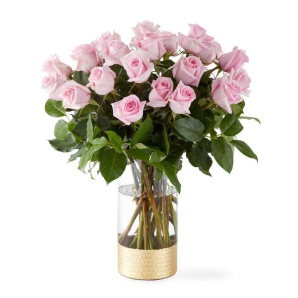 Pink roses arranged in a clear glass vase with a gold base