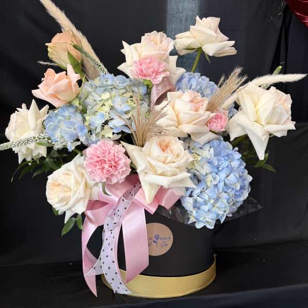 Bouquet of cream roses, blue hydrangeas, and pink carnations in a black hat box