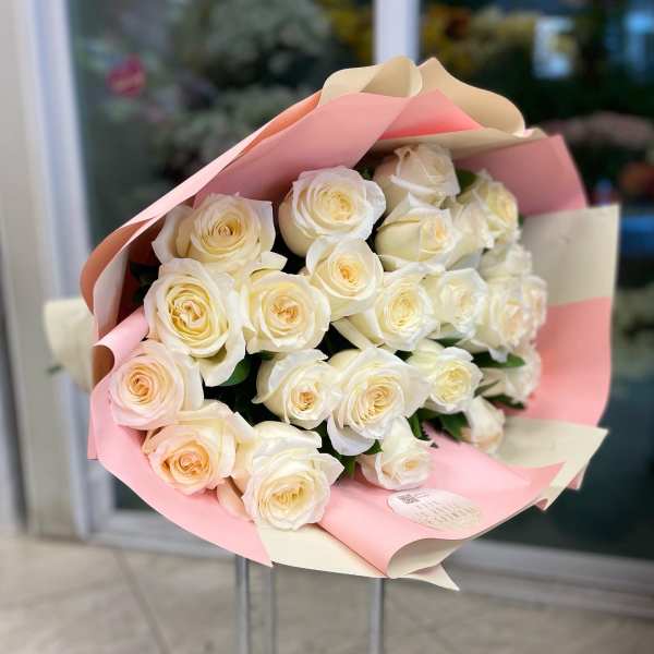 Bouquet of cream and pale pink roses wrapped in pink paper