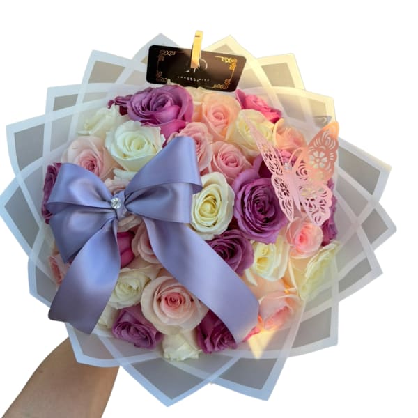 Bouquet of pastel roses with a lavender ribbon and butterfly wrap