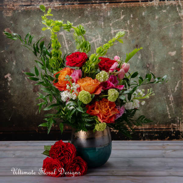 Mixed bouquet in a dark vase with red, orange, pink, and green flowers