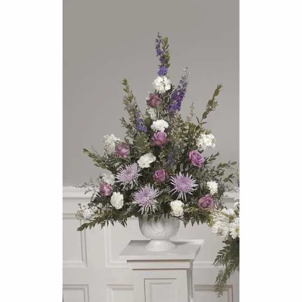 Tall floral arrangement in a white urn with purple and white blooms