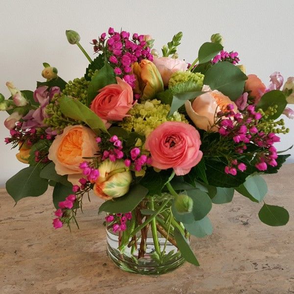 Mixed bouquet of pink and peach flowers in a clear glass vase