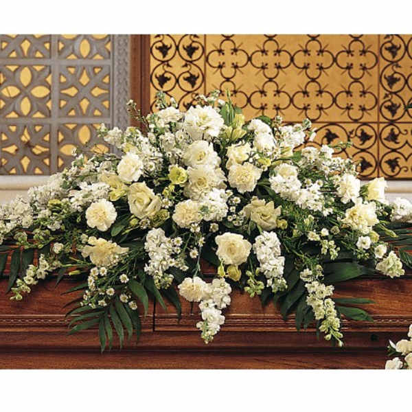 Large white floral arrangement on a wooden casket