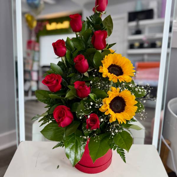 Red roses and sunflowers arranged in a pink box