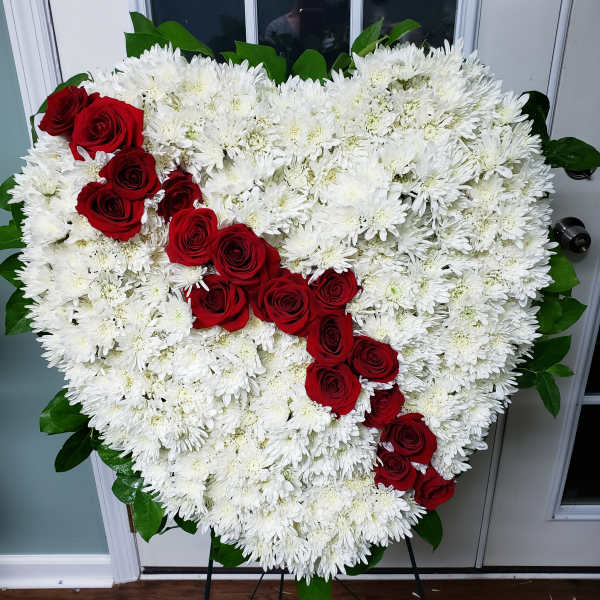 Heart-shaped white chrysanthemum arrangement with red roses on an easel