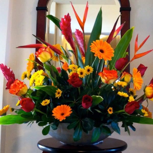 Tropical bouquet with orange and red flowers in a bowl vase