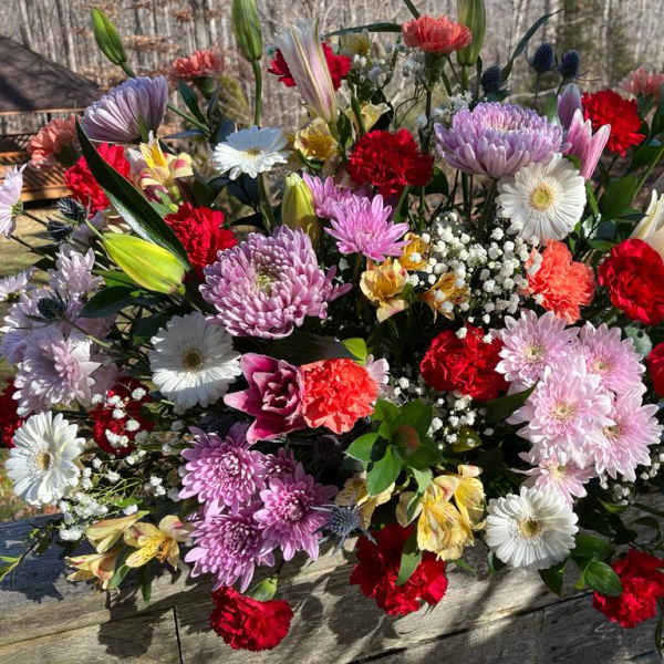Large mixed bouquet of colorful flowers laid on a wooden surface