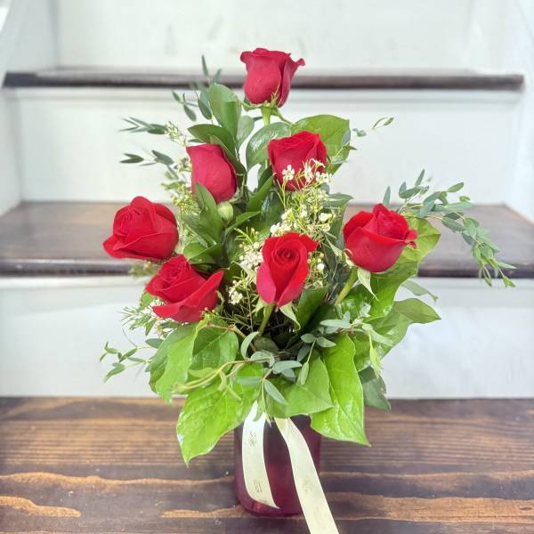 Bouquet of red roses in a burgundy vase with a ribbon