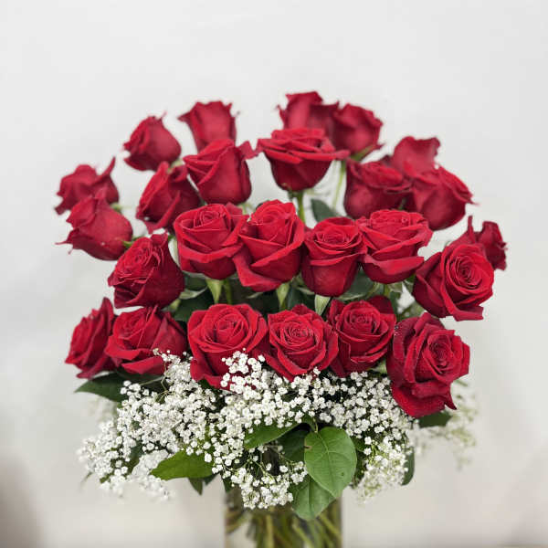 Red roses arranged in a clear glass vase with white baby's breath