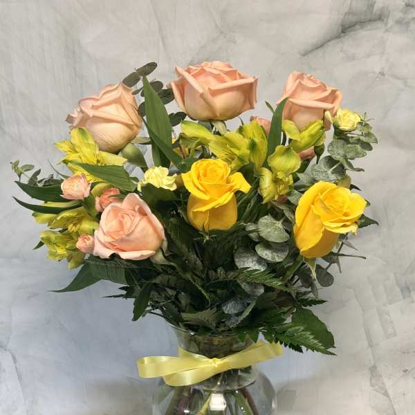 Peach and yellow roses with yellow alstroemeria in a glass vase