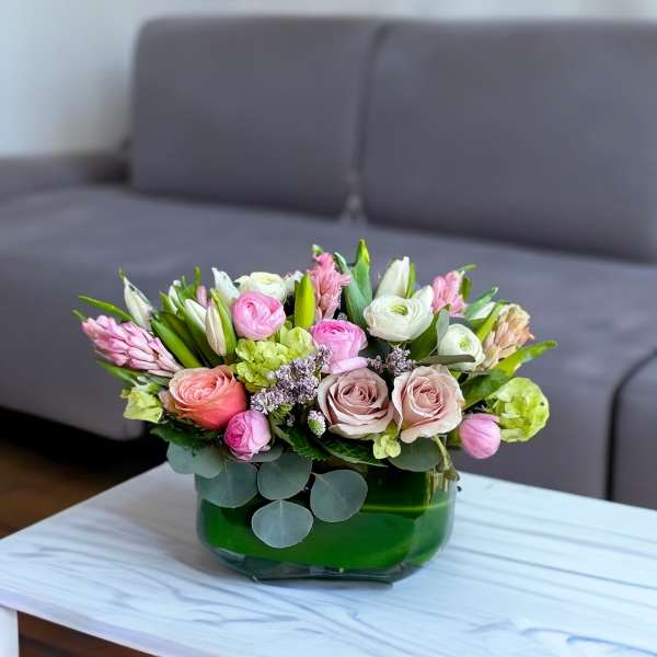 Pink and white flowers arranged in a green glass vase