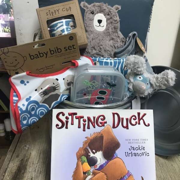 Baby gift basket with bibs, sippy cup, plush toys, and a book