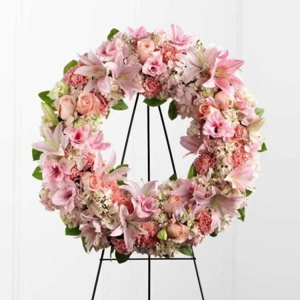Pink floral wreath on a black stand