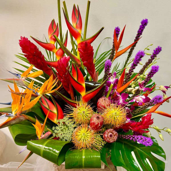 Tropical bouquet with red heliconia, orange bird of paradise, and purple orchids