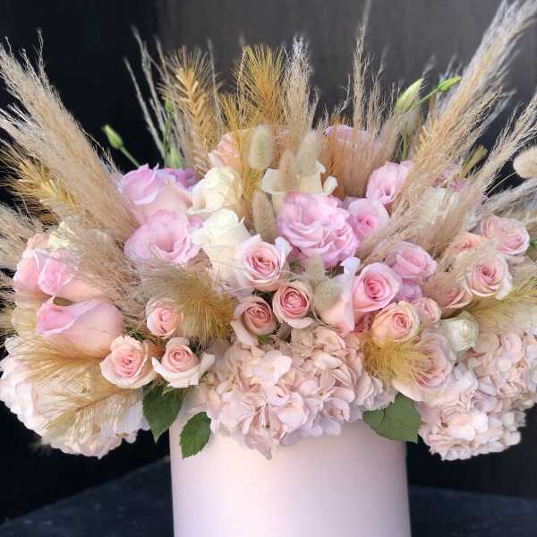 Pink roses and hydrangeas in a pale pink vase with dried grasses