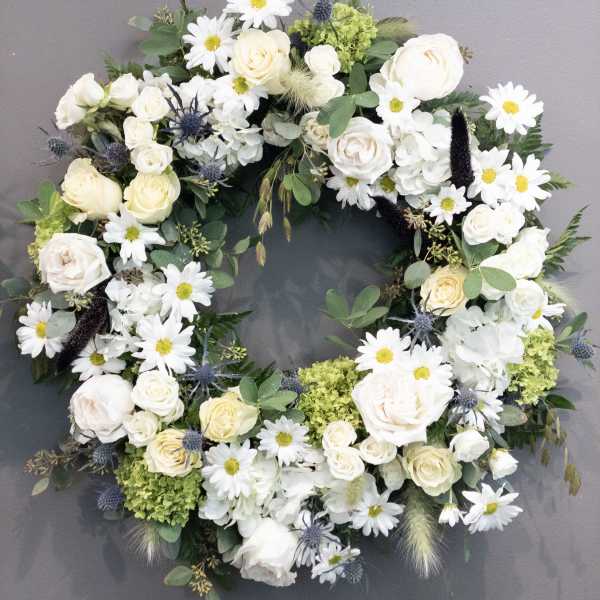 White and cream floral wreath with roses, daisies, and hydrangeas on a gray background
