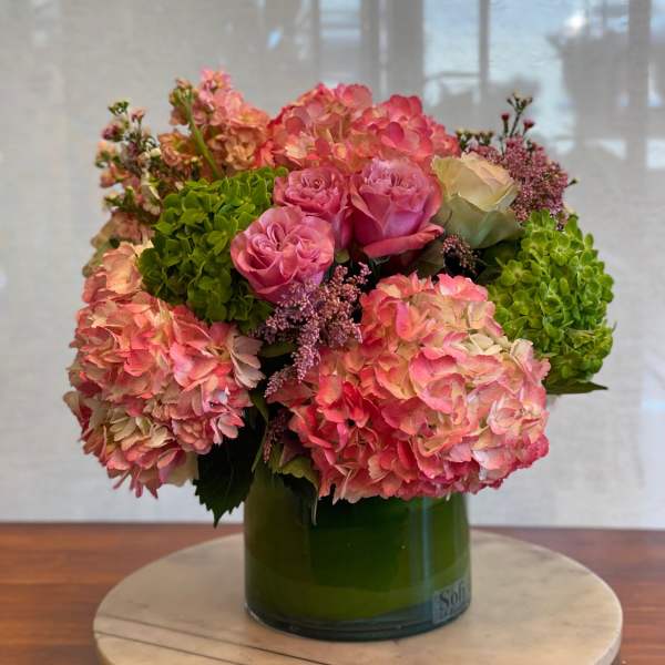Pink and peach hydrangeas with roses in a green glass vase
