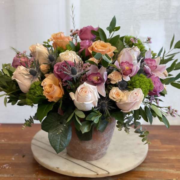 Mixed bouquet of roses and orchids in a ceramic vase