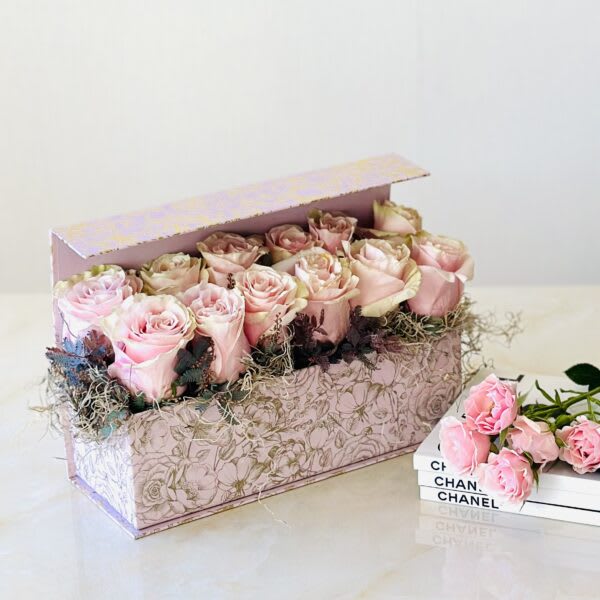 Pink roses arranged in a decorative floral box with a matching lid