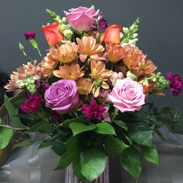 Mixed bouquet of roses, chrysanthemums, and snapdragons in a glass vase