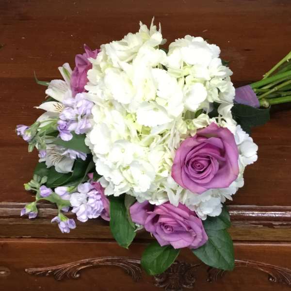 Hand-tied bouquet of white hydrangeas with purple roses and light lavender accent flowers