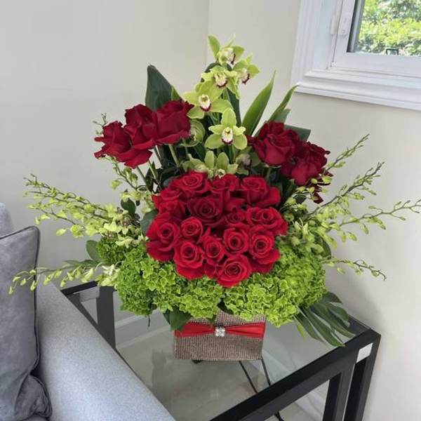 Red roses and green orchids arranged in a decorative box